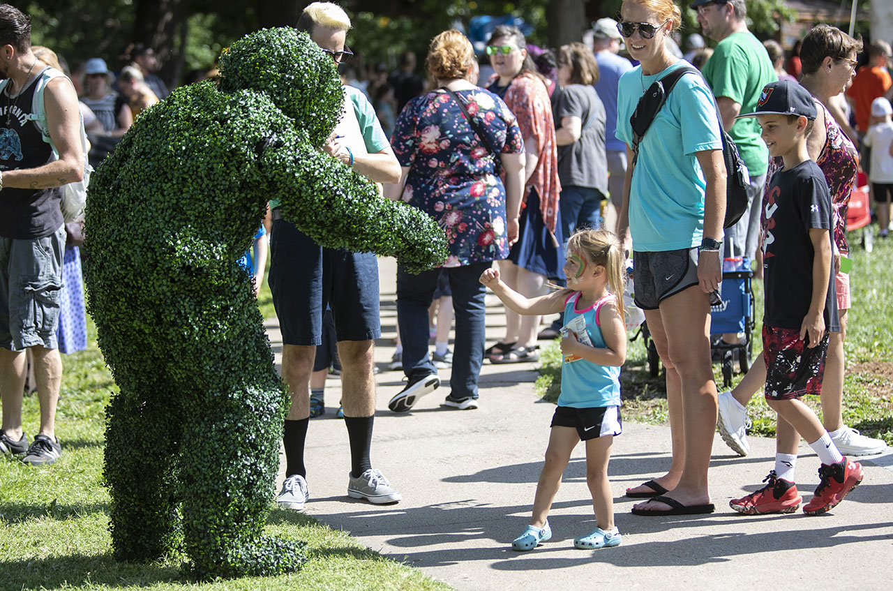 Child giving roving bush a fist bump.